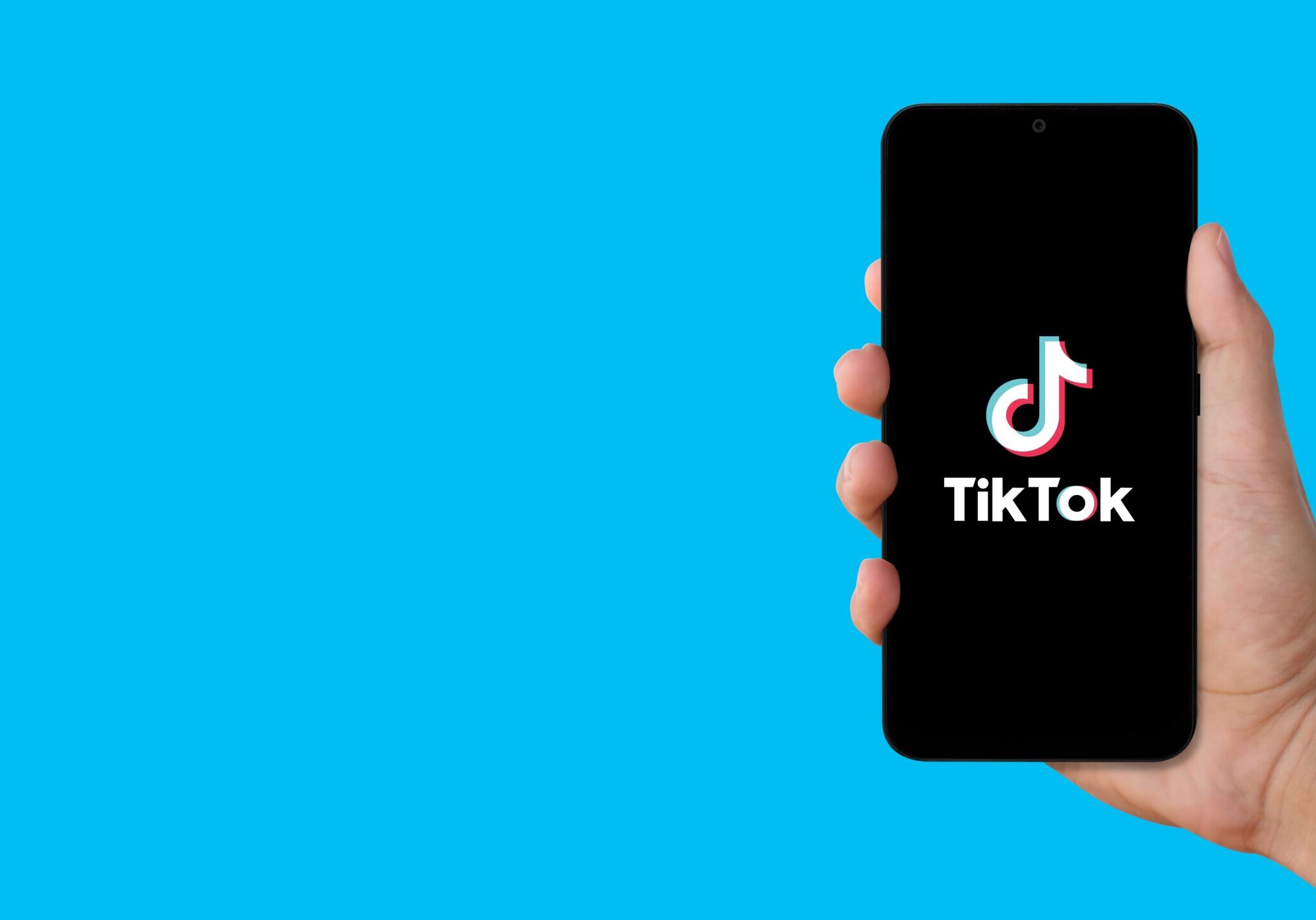 person holding up phone with TikTok logo on it