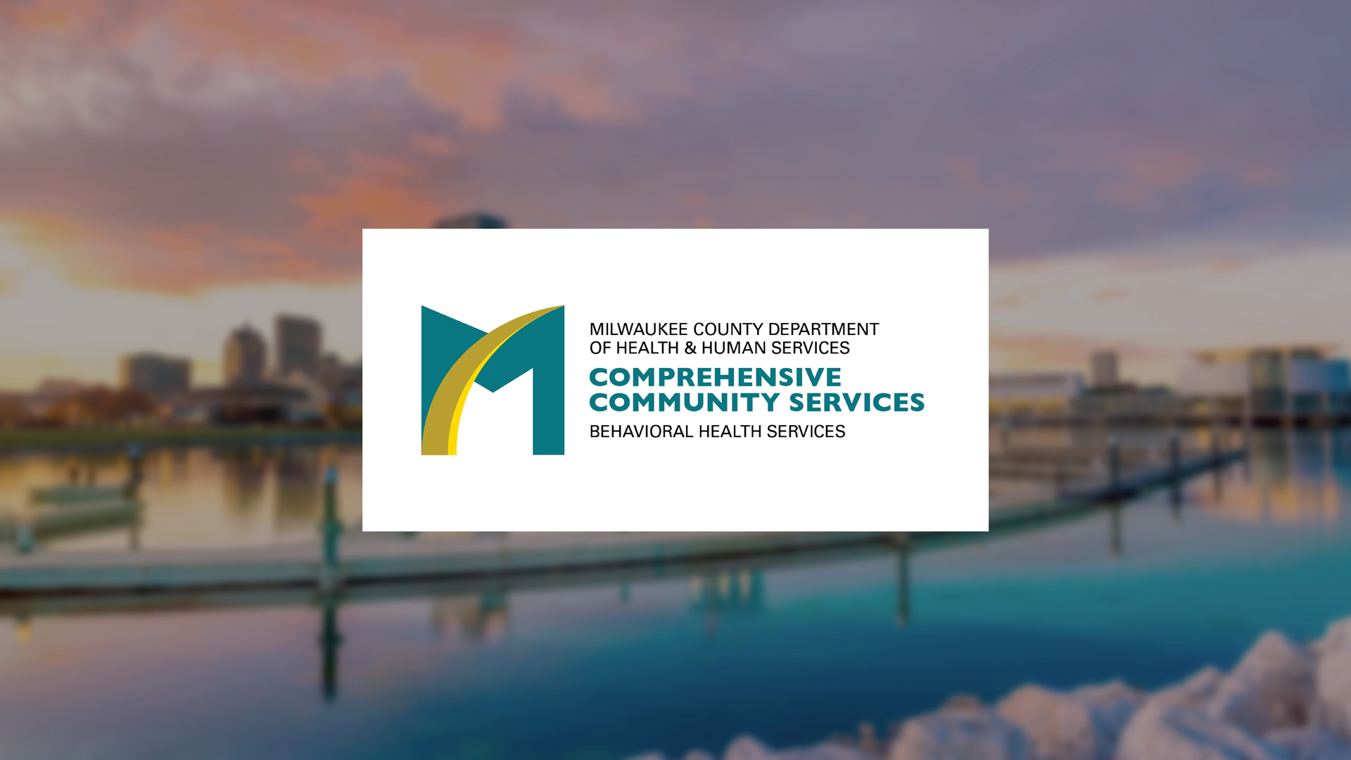 Milwaukee County Health & Human Services Comprehensive Community Services logo on a white panel over a blurred waterfront cityscape background.